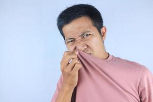 Asian man check his own smell, sniffing his wet armpit or sweating, isolated on white background photo