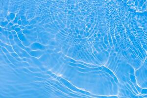 Blue water with ripples on the surface. Defocus blurred transparent blue colored clear calm water surface texture with splashes and bubbles. Water waves with shining pattern texture background. photo