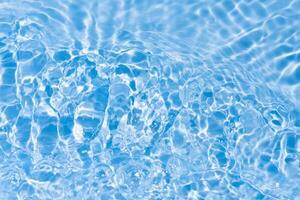 Blue water with ripples on the surface. Defocus blurred transparent blue colored clear calm water surface texture with splashes and bubbles. Water waves with shining pattern texture background. photo