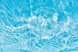 Blue water with ripples on the surface. Defocus blurred transparent blue colored clear calm water surface texture with splashes and bubbles. Water waves with shining pattern texture background. photo
