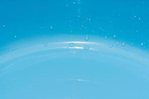 Blue water with ripples on the surface. Defocus blurred transparent blue colored clear calm water surface texture with splashes and bubbles. Water waves with shining pattern texture background. photo