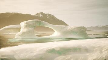 An iceberg floating in a body of water with mountains in the background video