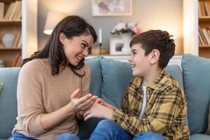 Happy and smiling mother and son resting and spending time together on a holiday. Relax, happiness and calm woman and her child sitting on a sofa and hugging in a room of their family home. photo