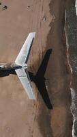 Military secret plane on the shore of the sea. Action. Aerial top view of an abandoned plane on a sand beach. video