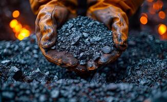 A person is holding a pile of coal in their hands. The scene has a somber and heavy mood, as the coal is often associated with pollution photo