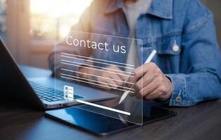 Communication and Contact us or Customer support hotline people connect. Hand using a laptop and touching on virtual screen contact icons, email and address, live chat with internet wifi. photo