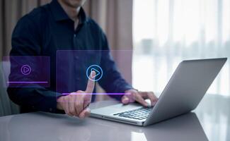 A person is pointing at a screen with playing. The screen is lit up and has a blue background. streaming online, watching on internet education on internet and e-learning concept. photo