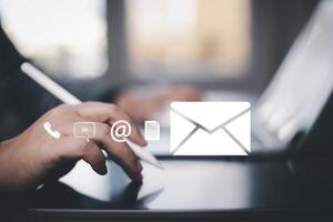 Communication and Contact us or Customer support hotline people connect. Hand using a laptop and touching on virtual screen contact icons, email and address, live chat with internet wifi. photo