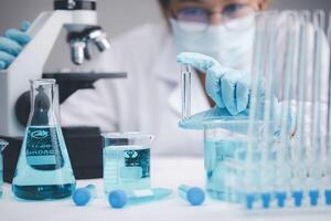 biochemical research scientist working with a microscope for the virus,Doctor man write a history of the experimental results in a , laboratory glassware containing chemical liquid for design. photo