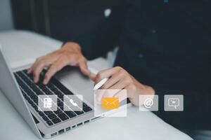 Communication and Contact us or Customer support hotline people connect. Hand using a laptop and touching on virtual screen contact icons, email and address, live chat with internet wifi. photo