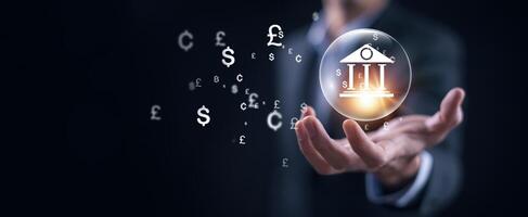 Businessman holding virtual bank with currency sign for forex exchange and global money transfer by technology concept. photo