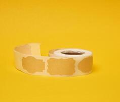 Sticky empty brown paper labels on tape, yellow background photo