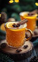 caliente condimentado Navidad té con naranja clavos de olor y canela servido en Clásico vaso tazas en rústico de madera tablero foto