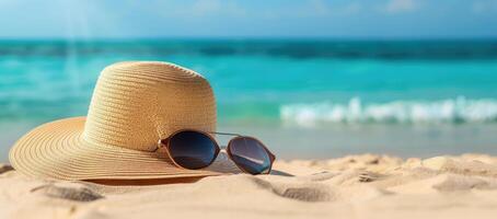 A straw hat with sunglasses on it is laying on the sand at the beach. The hat is positioned in a way that it casts a shadow on the sand. Concept of relaxation and leisure, as the hat photo
