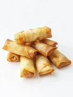 A stack of crispy, golden-brown spring rolls on a white background, perfect for appetizer or snack visuals. photo