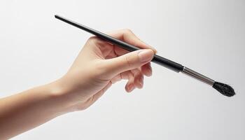 Close-up of a hand holding a paintbrush against a white background. Perfect for art, painting, and creativity concepts. photo