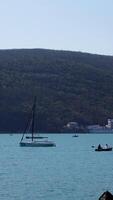 A beautiful bird's-eye view of the landscape. Action . A view of the blue ocean, mountains and green trees standing on them and you can see small sails that float near the shore. video
