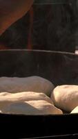 Dough being baked in frying pan in nature. Creative. Buns or pies are cooked in frying pan with fire. Cooking in frying pan with campfire in nature. Summer grill video