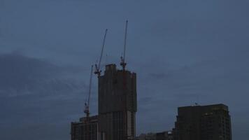 Time lapse of Silhouette, A construction site against a twilight sky, featuring cranes and building structures, highlighting the quiet yet industrious atmosphere of urban development. video