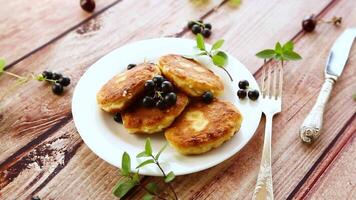 Fried curd cheese pancakes with black currants, on a wooden table video