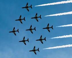 Airshow of military jet fighters. Group of military airplanes performs maneuvers with a smoke trace. Aviation background photo