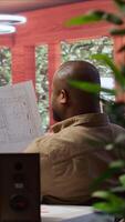 Vertical Entrepreneur analyzing architectural sketches and blueprints at his home, planning the layout and design of a new office to foster business development. Hunting for creative workspace. Camera B. video