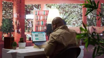 Business analyst calculating project funds and analytics at his home, allocating resources and solving tasks to accomplish objectives. Entrepreneur works on money management accounting. Camera B. video
