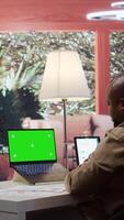Vertical Businessman reviewing statistics reports next to an isolated mockup screen at home office, adviser calculating budget in order to expand the enterprise activity. Finance and economy. Camera B. video
