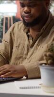 Vertical Self employed analyst working on financial audits and budget planning on his laptop, managing online marketing and development strategies for his personal trading business at home. Camera B. video