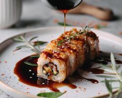 a plate with a sushi roll on it being poured with sauce photo