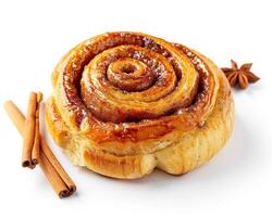 a cinnamon roll with cinnamon and star anise on a white surface photo