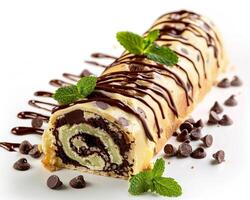 a roll of chocolate cake with chocolate drizzle and mint leaves photo