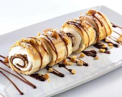 a roll of pastry with chocolate sauce and nuts photo