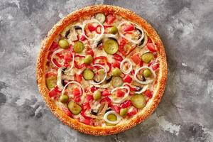 Pizza with edge sprinkled with sesame, cheese, mushrooms, pickles, tomatoes, bell peppers, onions and olives photo