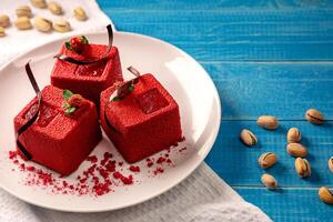 Red cube-shaped cakes with pistachio biscuit, chocolate souffle, raspberry confit and nut crumbs photo