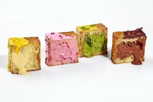 Cubed croissant halves with fillings of vanilla and berry custard, pistachio and chocolate cream photo