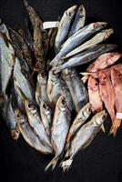 Dried salted roach, sabrefish, red mullets and gobies on black background photo