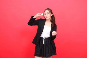 gesture of young asian office woman smiling elegantly wearing black formal suit both hands bringing crypto bitcoin up and showing it, for financial content, business, advertising, investment photo