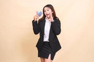 Beautiful formal indonesia office woman in suit standing holding debit credit card and telling to pay easy transaction on yellow background for commercial, vacancy and business photo