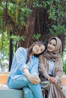 Friendship indonesia woman smiling on shoulder looking at camera in campus park. student for the concept of human interest and lifestyle photo