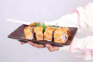 a plate closeup and front angle containing a sushi dish Japanese food held in both hands by a woman for culinary, food and lifestyle content photo