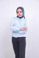 young Asian office woman wearing a hijab, blue shirt, standing smiling, holding her arms crossed. Beautiful Muslim women use business, finance and fashion content photo