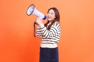 Asian woman expression shouting smile to camera standing to two hands holding megaphone loudspeaker for warning. for fashion, business and broadcast concepts photo