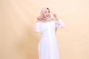 woman indonesia muslim standing to the camera smile happy both hands pointing up. Fashion, pointer, business and promotion concept photo