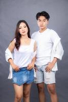 elegant men and women are posing standing in front of the camera with their shirts open, their hands to their waists facing forward in an indoor setting. fashion promotion couple photo session in stud