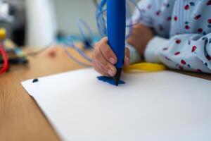 Close-up of girl creating plastic 3D model on paper at table photo