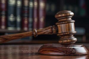 Close-up of a wooden judge's gavel on its sound block, placed on a polished courtroom table, representing the judicial system and justice administration photo
