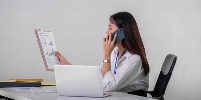 Asian Businesswoman Discussing Data Analysis Over Phone in Office Setting photo