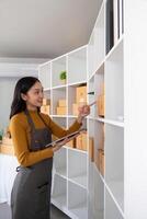 Ecommerce business owner managing inventory and checking stock in home office. Small business entrepreneur organizing packages for shipment and using a tablet for inventory tracking photo