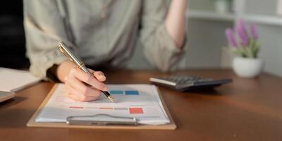 Businesswoman using laptop computer and working at office with calculator document on desk, doing planning analyzing the financial report, business plan investment, finance analysis concept photo